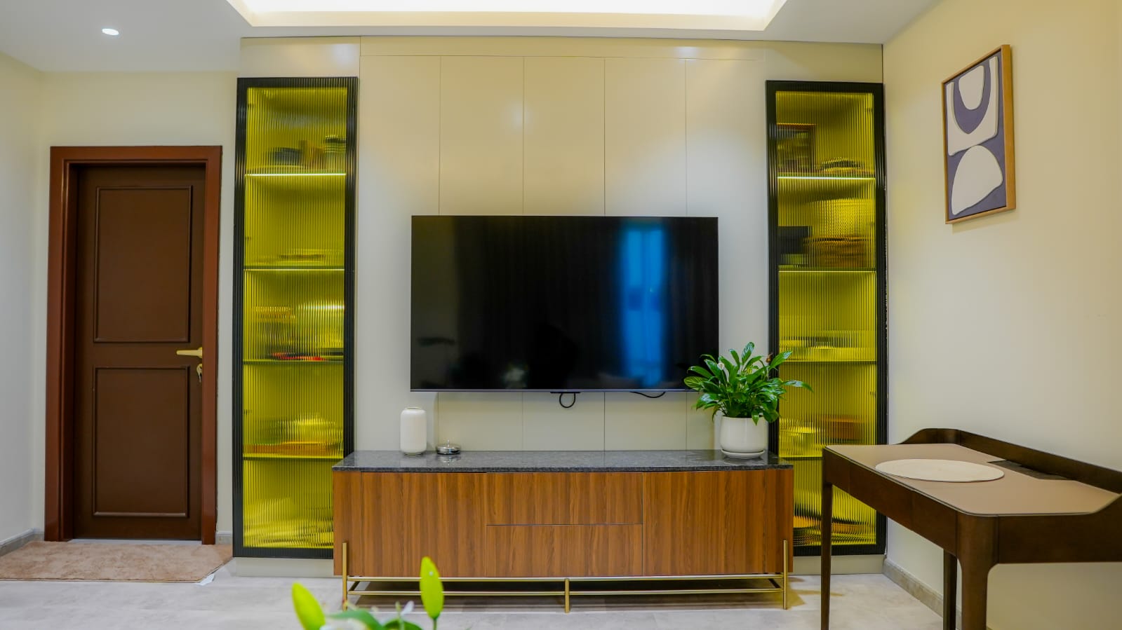 Living Legends — Majan, Dubai: TV feature wall with amber reeded-glass cabinetry